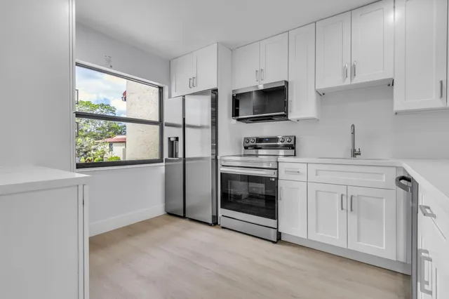 a kitchen with stainless steel appliances a sink a stove a refrigerator a counter top space and cabinets