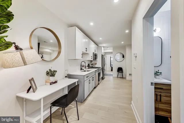 a large white kitchen with a sink and a refrigerator