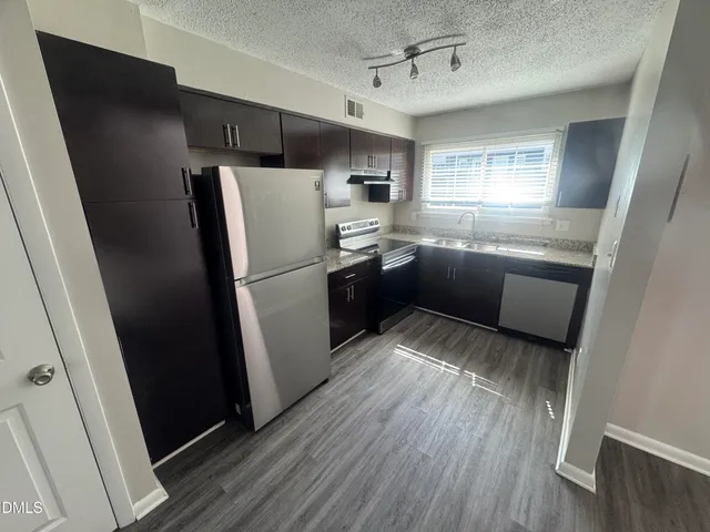 a kitchen with stainless steel appliances a refrigerator a sink a stove a refrigerator and cabinets