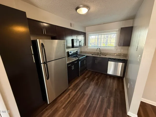 a kitchen with stainless steel appliances granite countertop refrigerator a sink a stove and cabinets