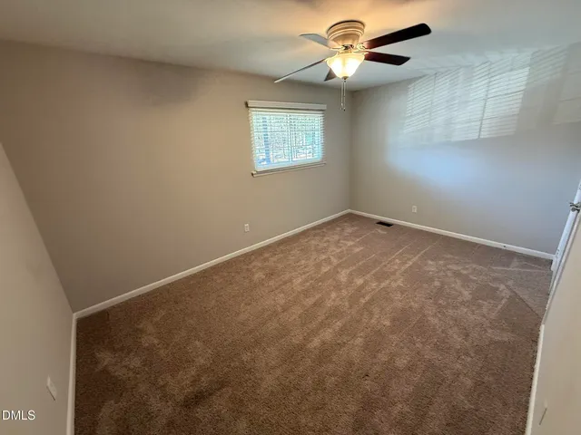 an empty room with a window and a fan