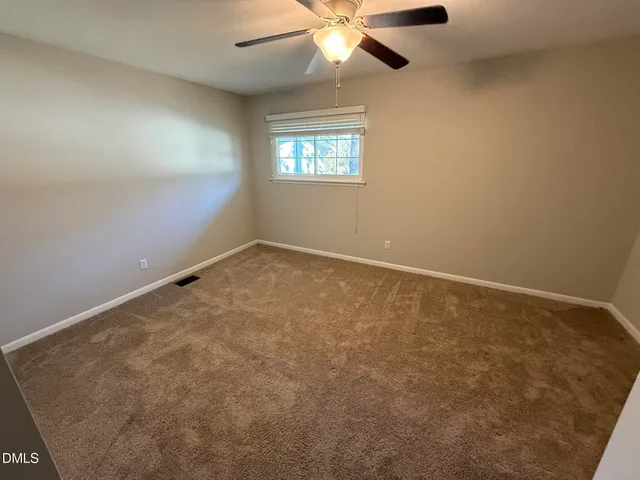 an empty room with windows and chandelier fan