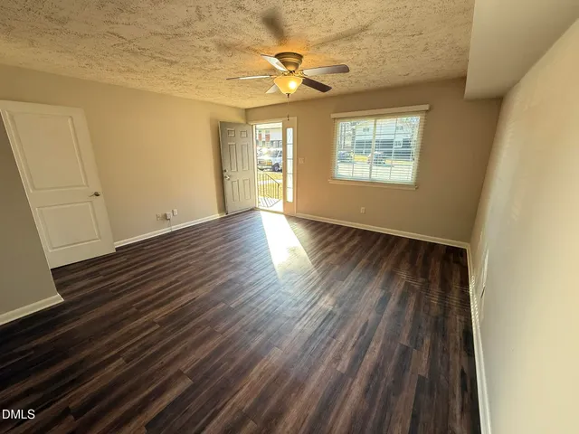 a view of an empty room with a window and wooden floor