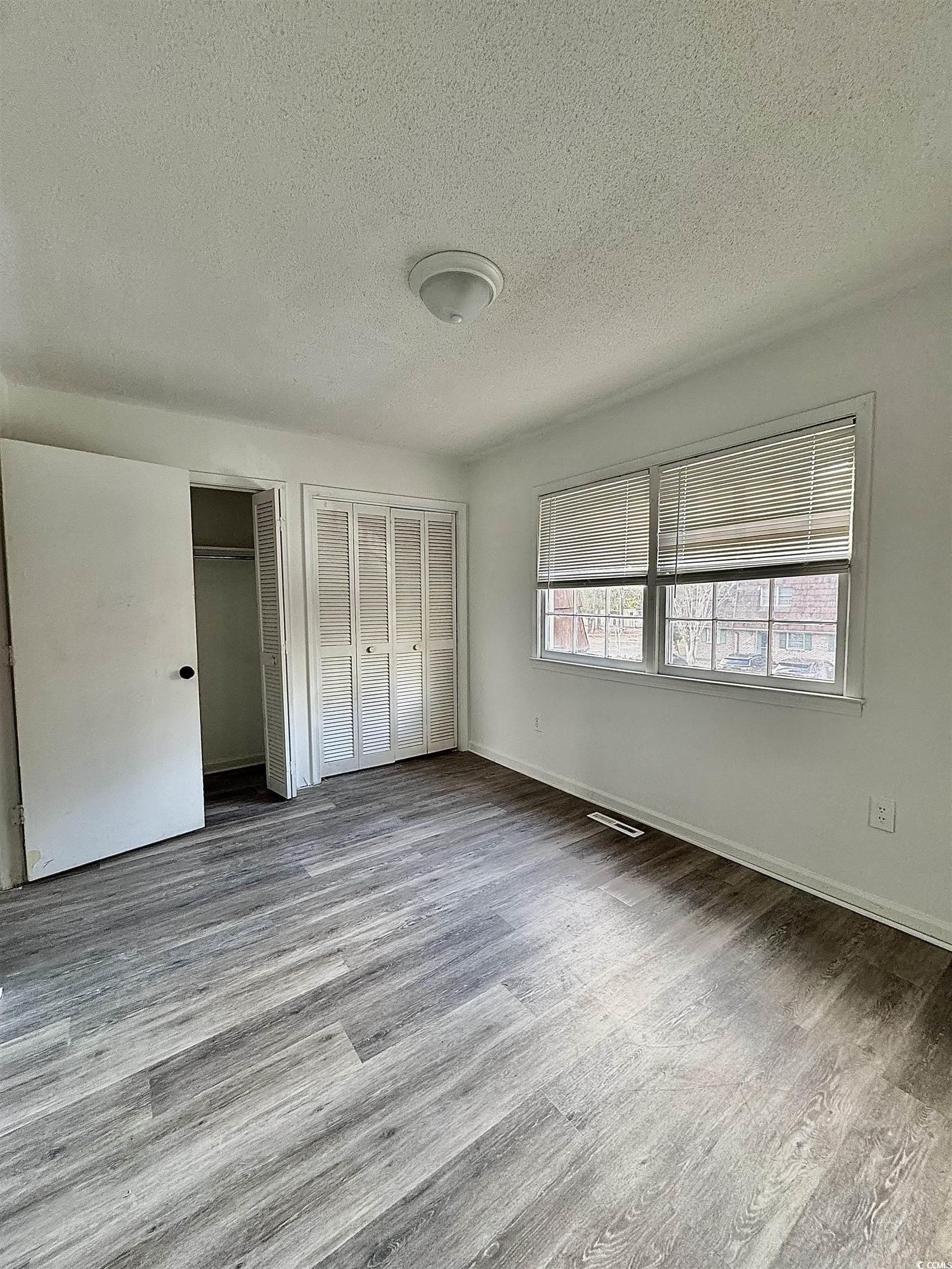 1025 Carolina Road, Unit H4 Conway, SC 29526 - Photo 5 of 10 Unfurnished bedroom with two closets, a textured ceiling, and wood finished floors