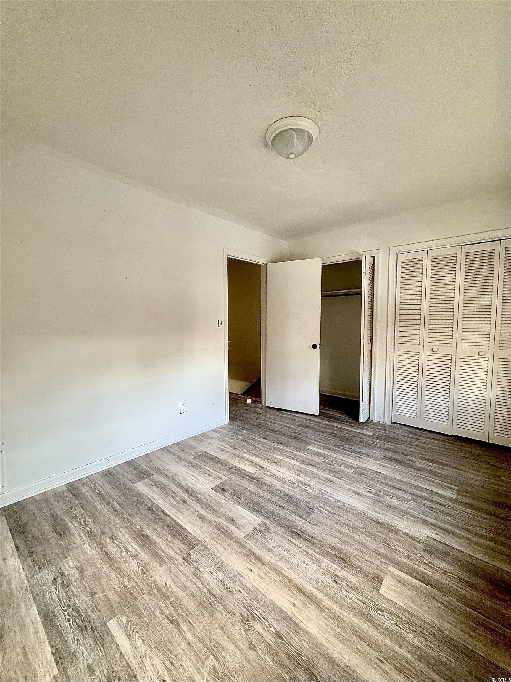 1025 Carolina Road, Unit H4 Conway, SC 29526 - Photo 7 of 10 Unfurnished bedroom with multiple closets, wood finished floors, and a textured ceiling