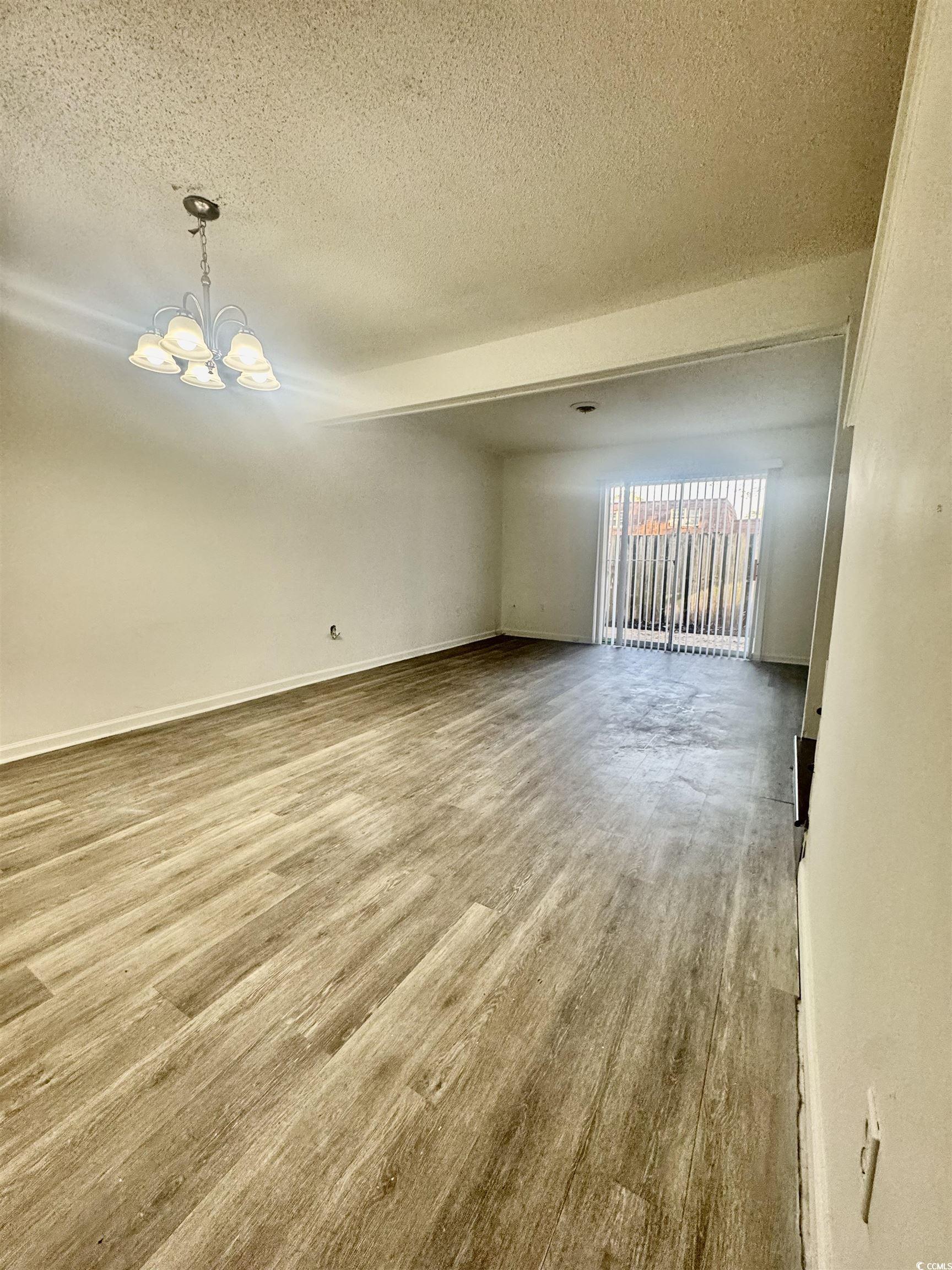1025 Carolina Road, Unit H4 Conway, SC 29526 - Photo 10 of 10 Unfurnished room featuring a textured ceiling, a chandelier, and wood finished floors