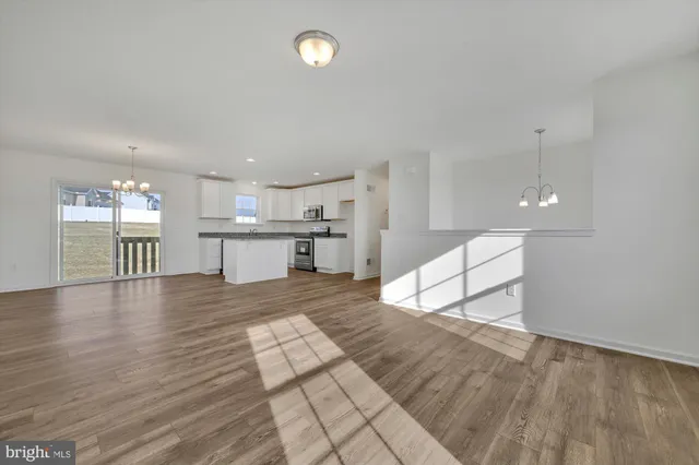 a kitchen with granite countertop a sink stainless steel appliances white cabinets and wooden floor