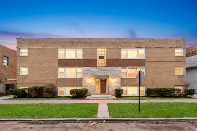 a front view of a building with a garden and plants