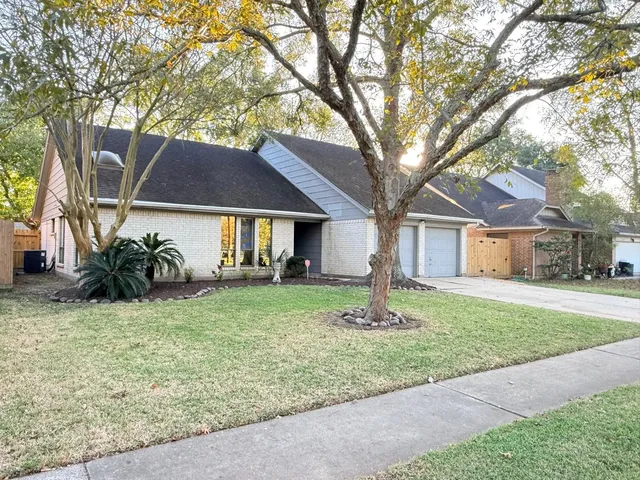 a front view of a house with a garden and trees