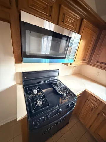a kitchen with stainless steel appliances granite countertop a stove a sink and a microwave