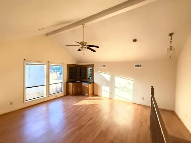 a view of an empty room with wooden floor and a window