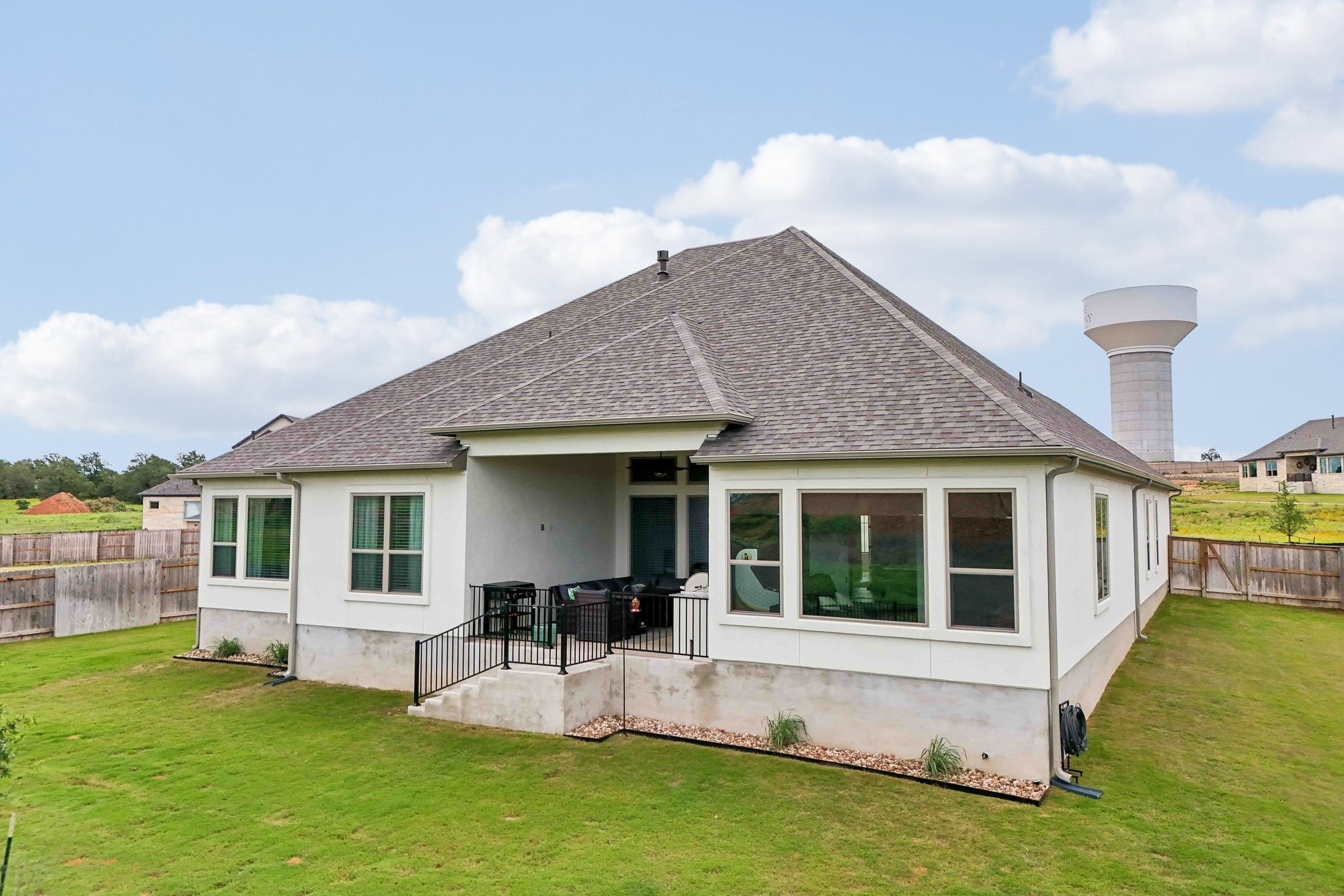 130 Firethorn Loop Bastrop, TX 78602 - Photo 30 of 38 Rear exterior featuring an expansive grassy yard, covered patio, and multiple large windows