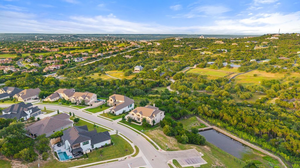 215 Lodestone Lane Austin, TX 78738 - Photo 40 of 40 An aerial perspective reveals a harmonious community nestled amidst verdant hills and a serene pond.