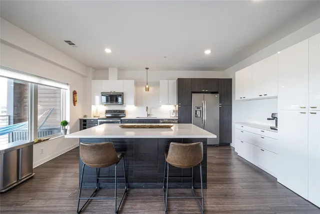 a kitchen with stainless steel appliances granite countertop a stove a sink dishwasher a stove and white cabinets with wooden floor