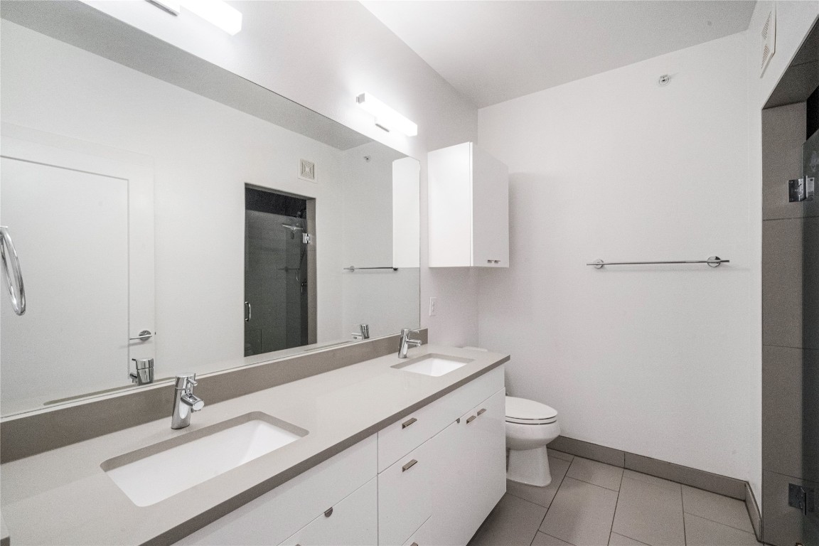 4361 South Congress Avenue, Unit 531 Austin, TX 78745 - Photo 10 of 21 a bathroom with a granite countertop sink a toilet and a mirror