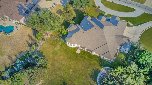 an aerial view of a swimming pool with a yard and plants