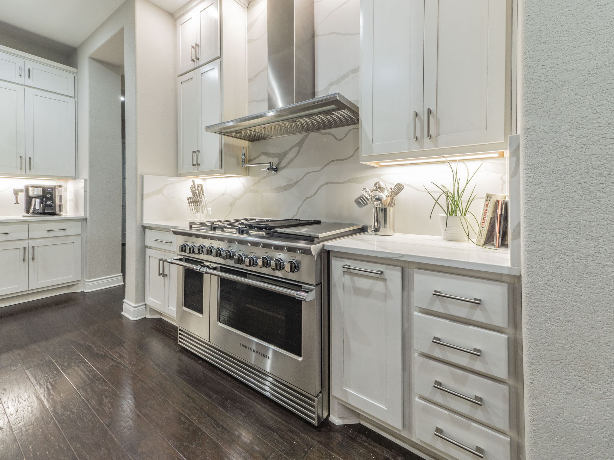 205 Standing Oak Drive Georgetown, TX 78633 - Photo 8 of 40 Kitchen with wall chimney exhaust hood, range with two ovens, white cabinets, dark wood-style floors, and light stone countertops