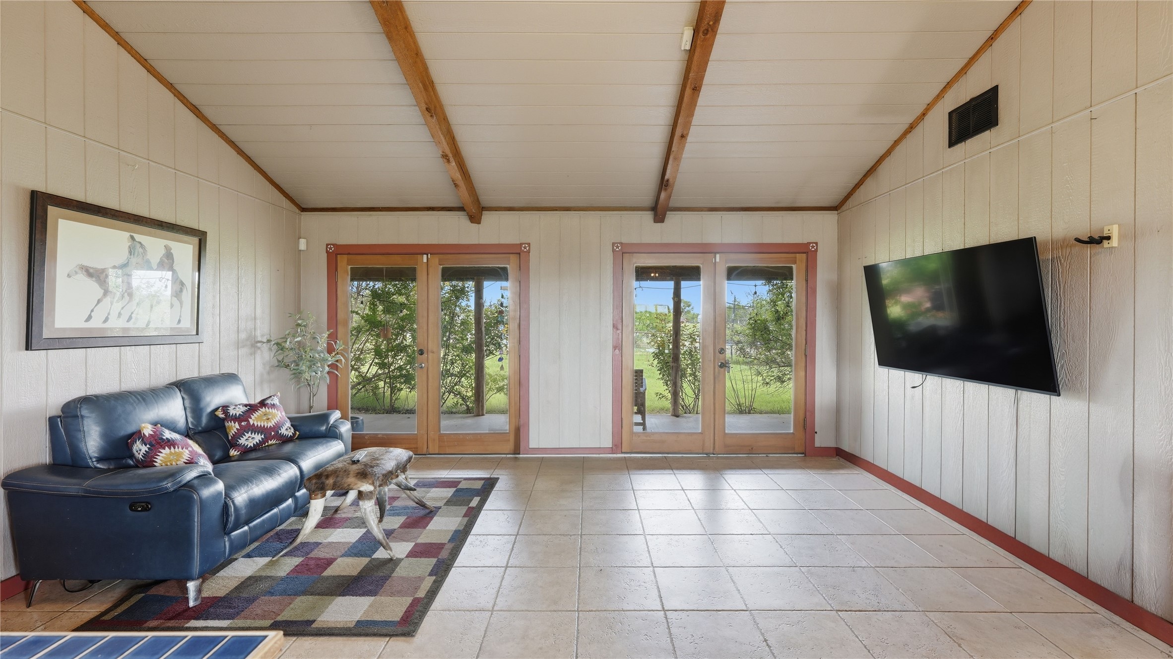 127 Offer Llano, TX 78643 - Photo 33 of 40 Spacious room featuring vaulted ceilings with exposed wood beams, tile flooring, and light-toned vertical paneling