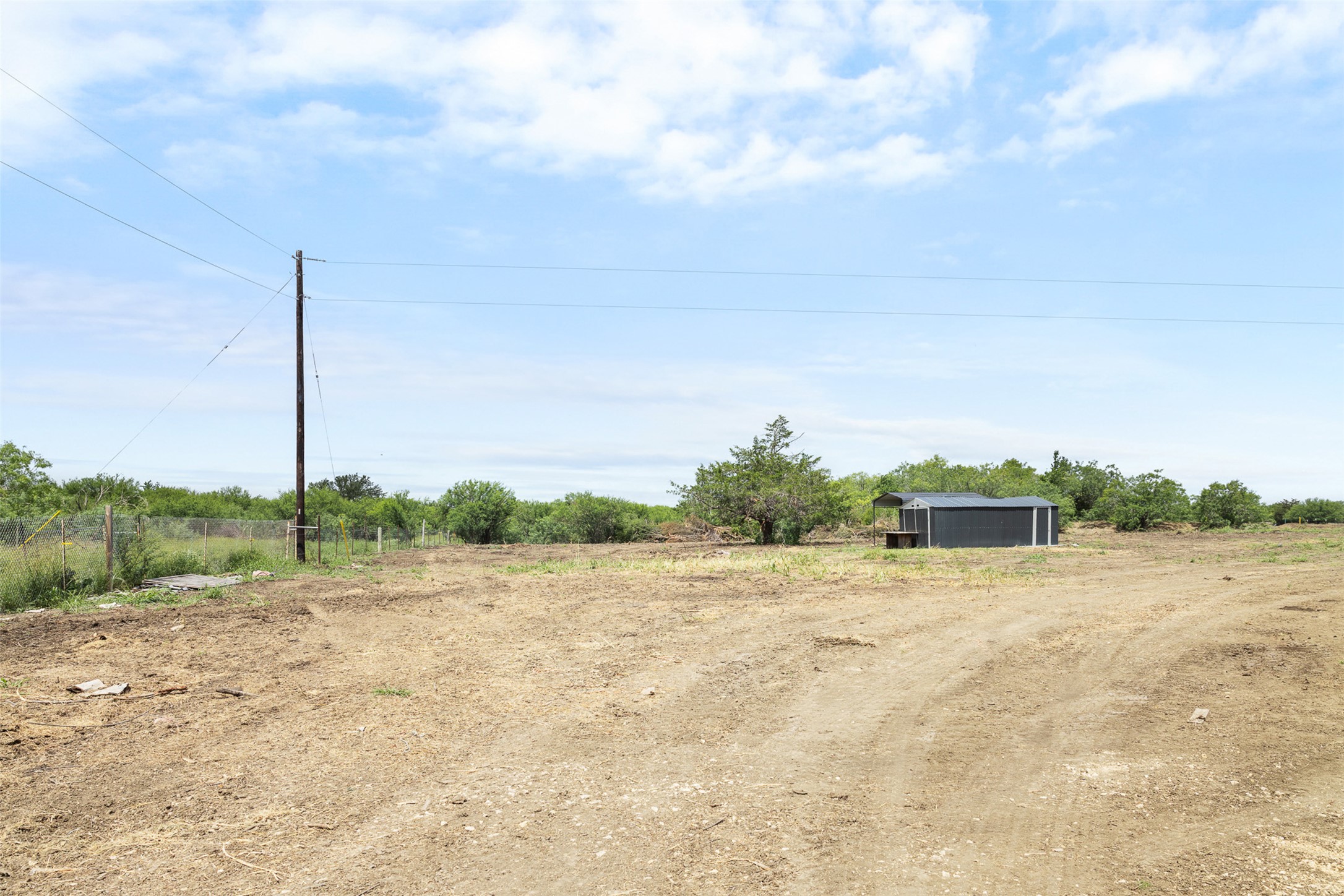 3315 Dry Creek Road Lockhart, TX 78644 - Photo 2 of 26 A spacious, cleared lot with potential, featuring a modest outbuilding and natural surroundings.