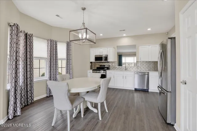 a view of a dining room and livingroom with furniture wooden floor a chandelier
