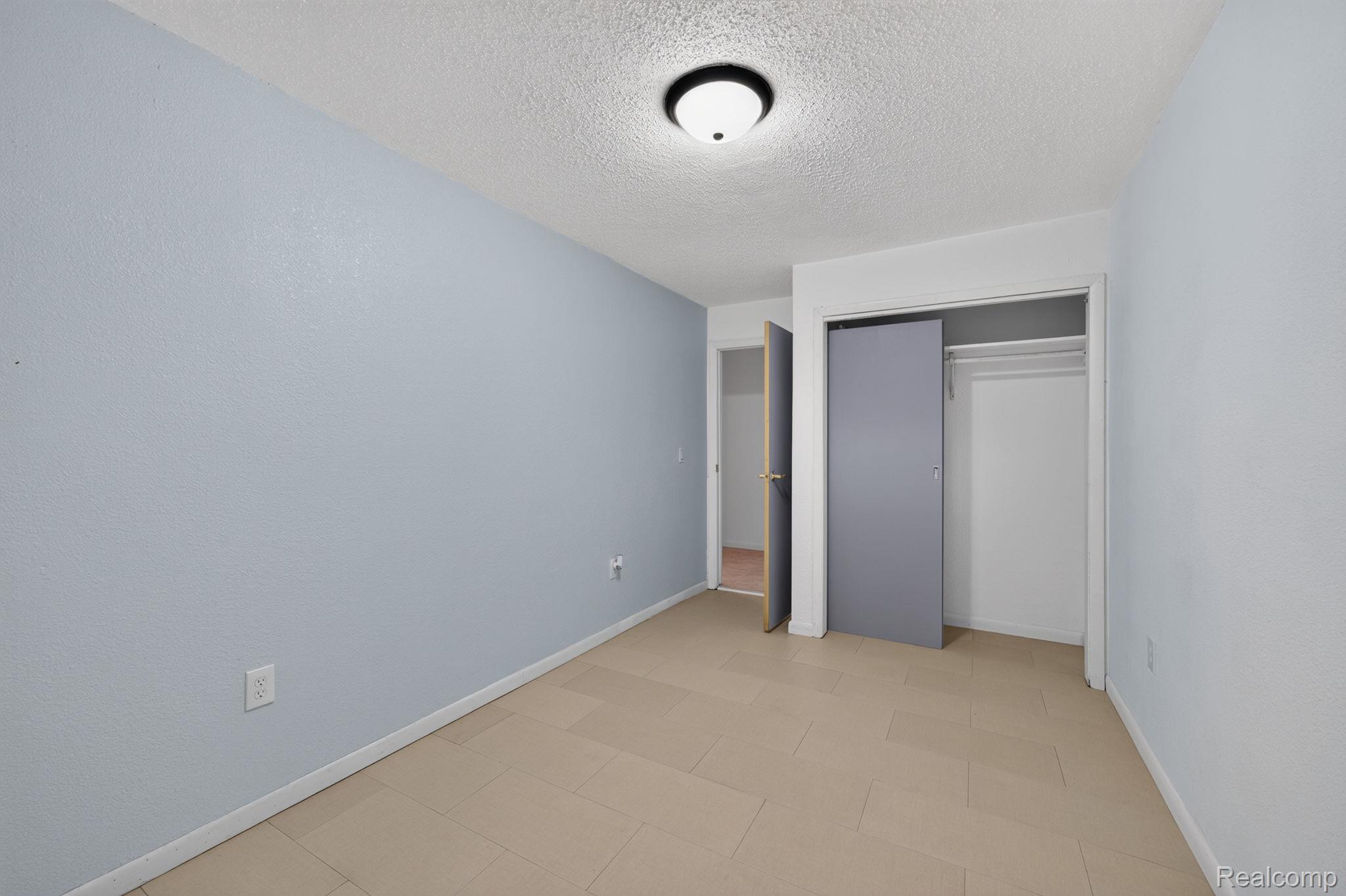 9288 Hilda Lane Flushing, MI 48433 - Photo 33 of 50 Bedroom featuring light blue walls, tiled flooring, an overhead flush-mount light fixture, and a built-in closet with sliding gray doors and internal shelving
