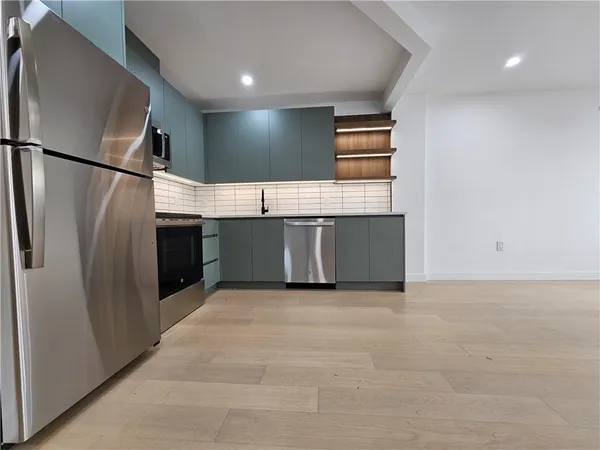 a view of kitchen with stainless steel appliances granite countertop refrigerator and sink