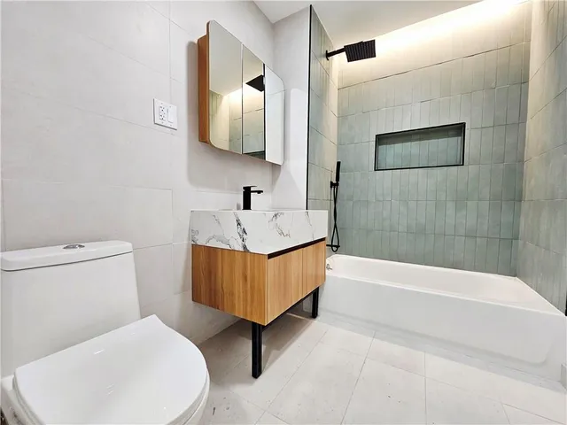 a white toilet sitting next to a bathroom sink and tub