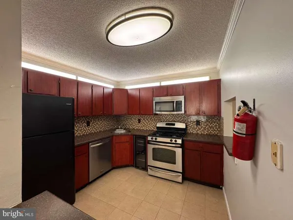 a kitchen with stainless steel appliances granite countertop a stove top oven a sink and a refrigerator