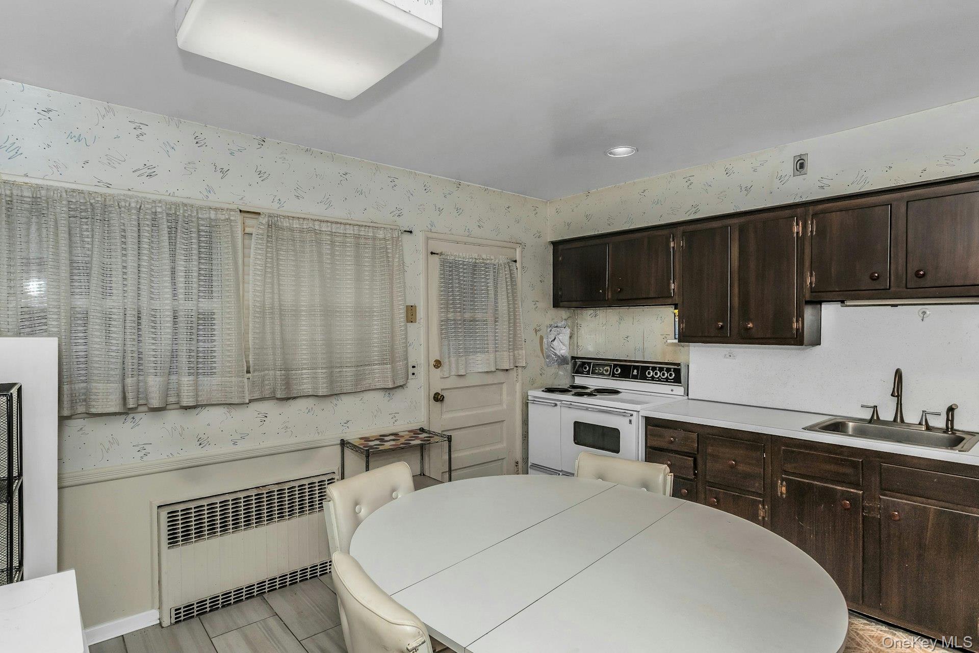 477 Demott Avenue Baldwin, NY 11510 - Photo 12 of 27 a kitchen with a sink a stove a microwave and wooden cabinets
