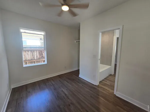 a view of an empty room with wooden floor and a window