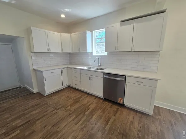 a kitchen with a sink cabinets wooden floor and a window