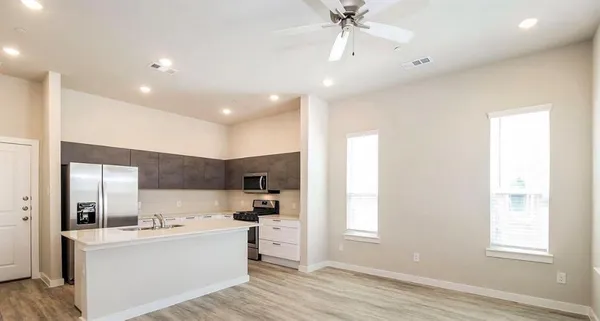 a large white kitchen with a refrigerator a stove a sink and a window