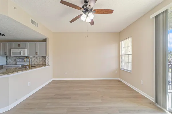 an empty room with wooden floor fan and windows