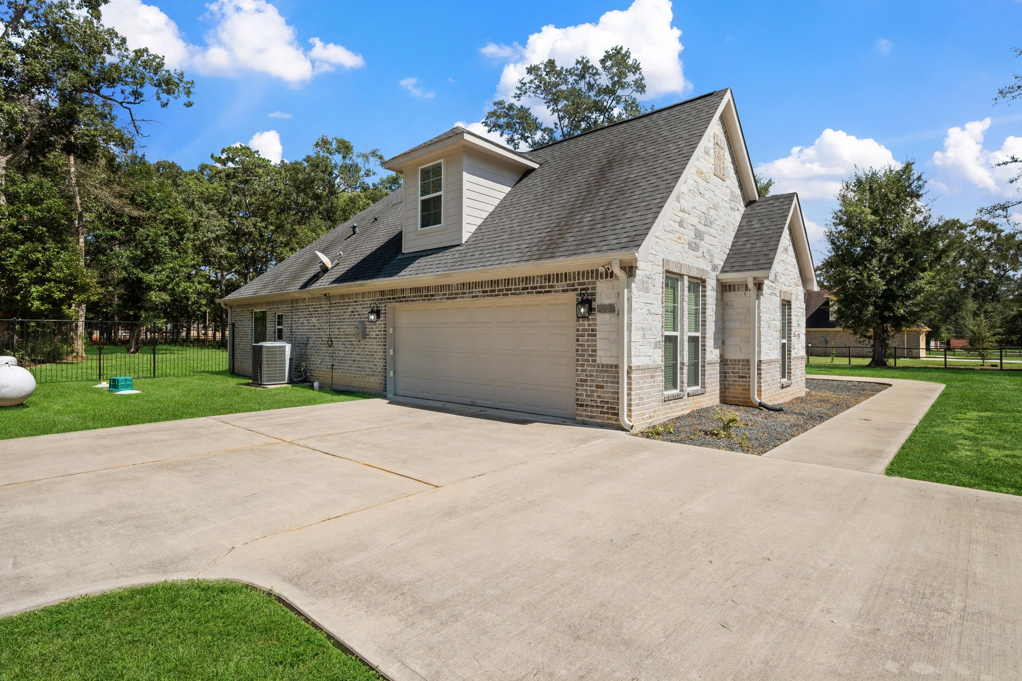 7815 Timber Switch Road Cleveland, TX 77328 - Photo 34 of 39 Charming stone-accented home with a spacious driveway, attached garage, and lush green surroundings, perfect for enjoying serene living.
