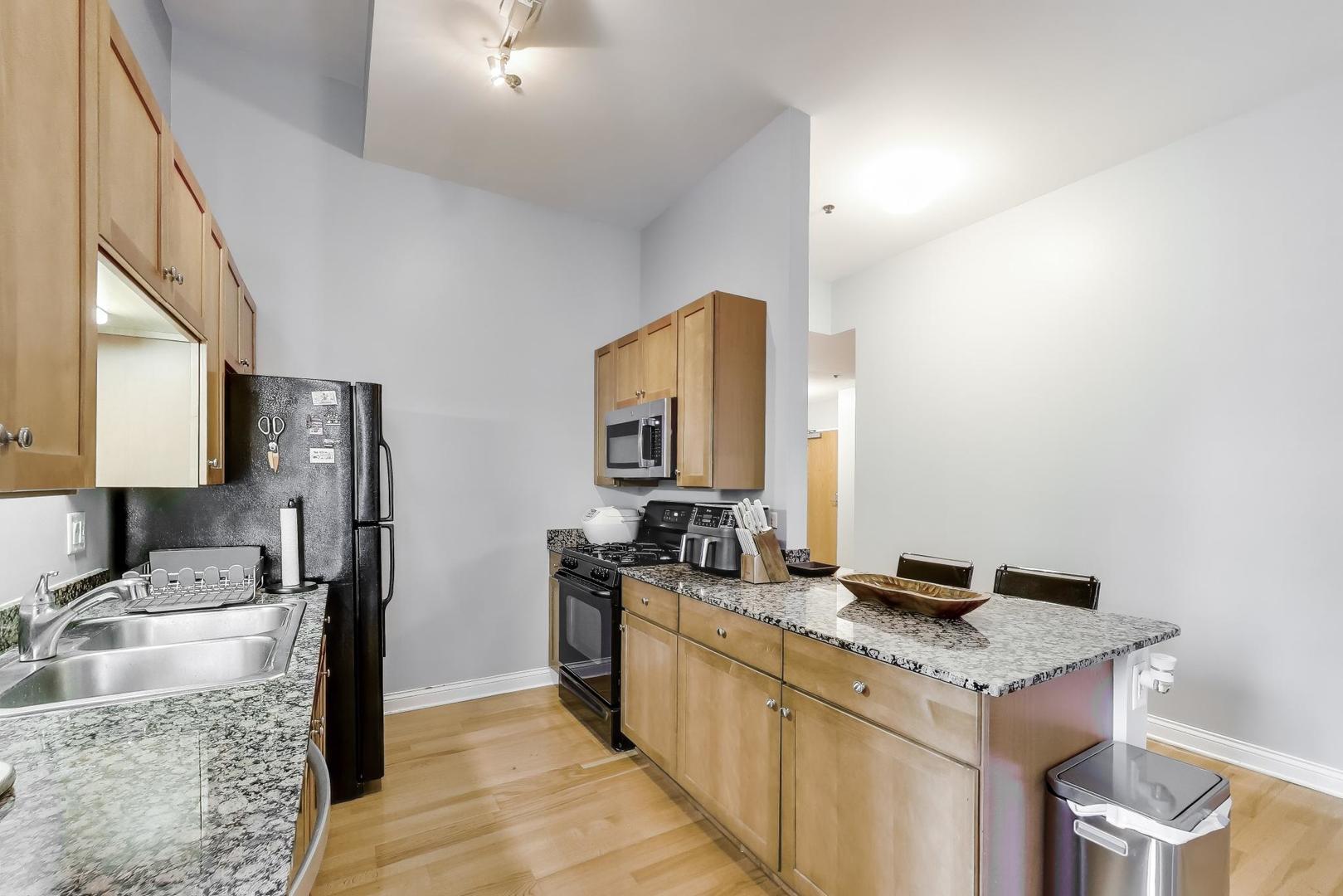 8 West Monroe Street, Unit 704 Chicago, IL 60603 - Photo 15 of 35 a kitchen with granite countertop a sink stove and refrigerator
