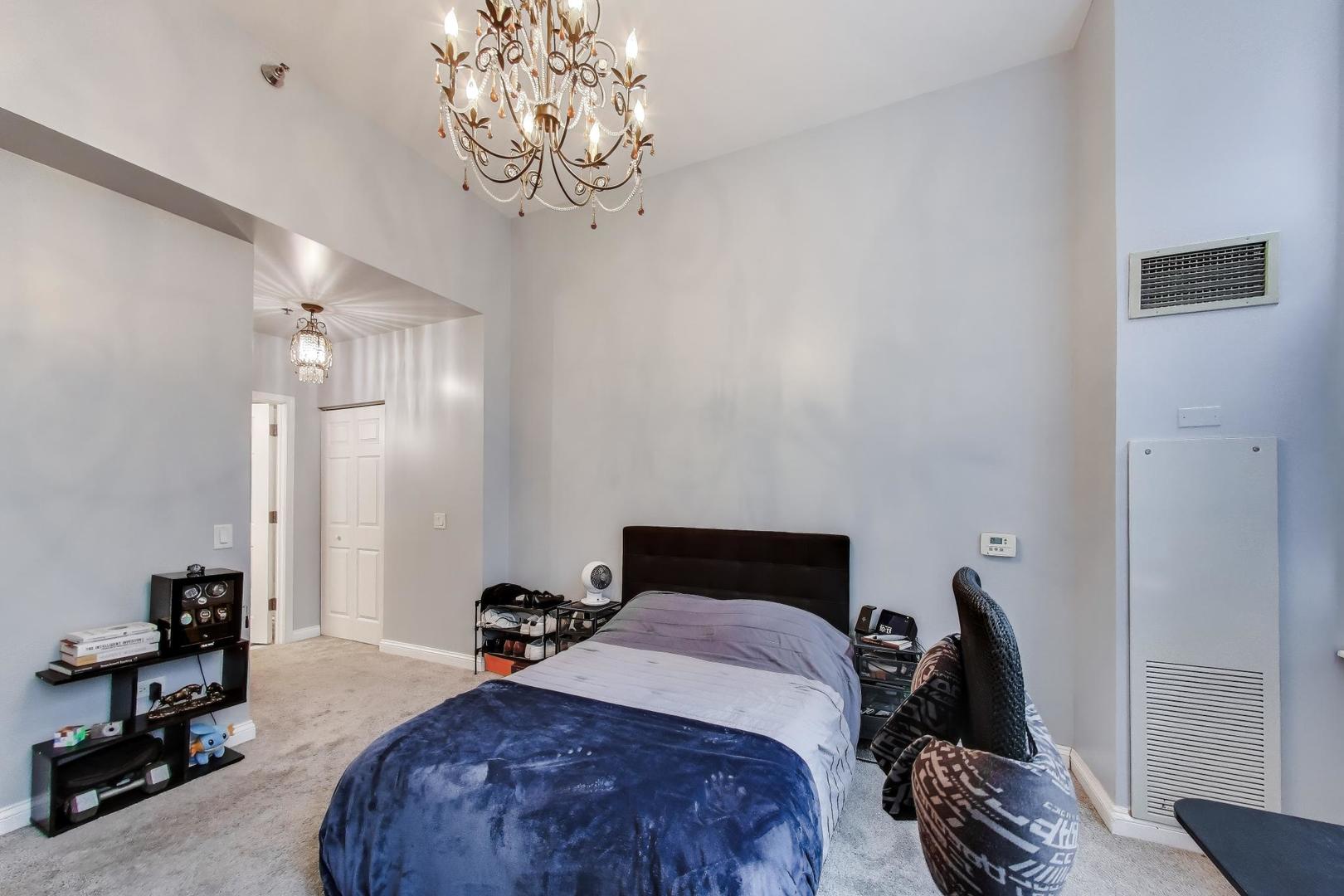 8 West Monroe Street, Unit 704 Chicago, IL 60603 - Photo 18 of 35 a bedroom with a bed and a chandelier