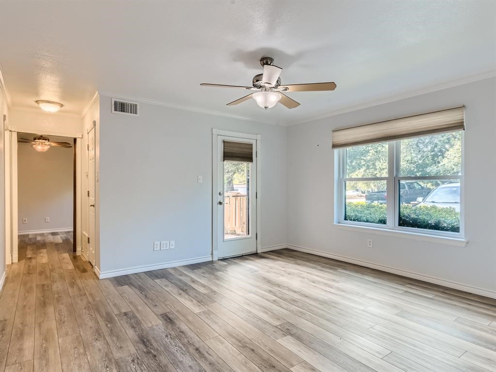 a view of empty room with wooden floor and fan