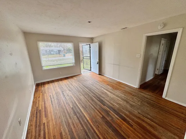 a view of an empty room with wooden floor and a window