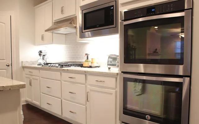 a kitchen with white cabinets and black appliances
