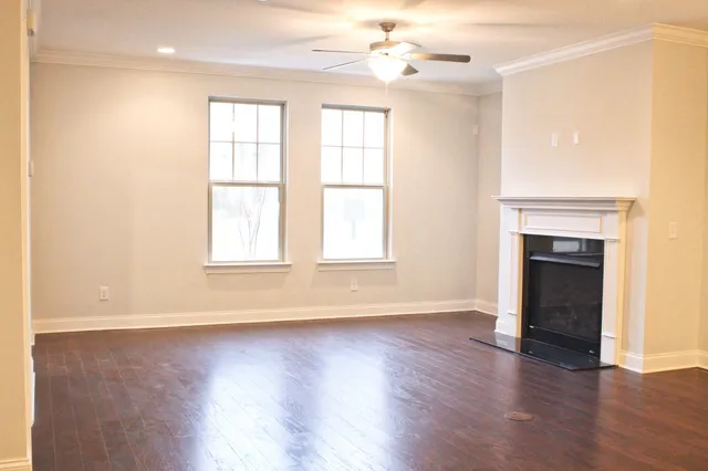 an empty room with wooden floor fireplace and windows