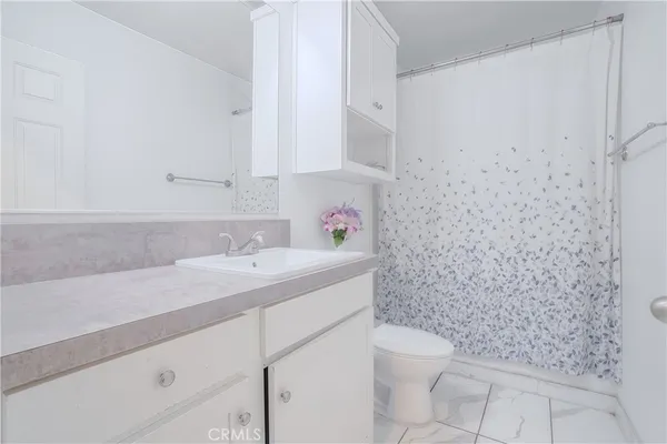 a bathroom with a granite countertop sink a toilet and a shower