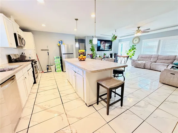 a view of kitchen with stainless steel appliances kitchen island granite countertop a stove a sink a dining table and chairs