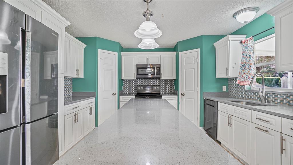 105 Caterham Way Kissimmee, FL 34758 - Photo 11 of 34 a large white kitchen with a refrigerator a stove a sink dishwasher and white cabinets with wooden floor