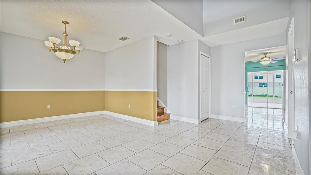 105 Caterham Way Kissimmee, FL 34758 - Photo 3 of 34 an empty room with wooden floor and chandelier