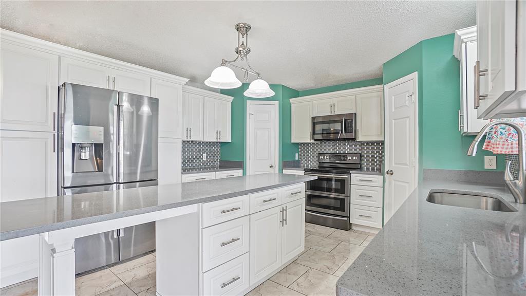 105 Caterham Way Kissimmee, FL 34758 - Photo 6 of 34 a kitchen with stainless steel appliances granite countertop a stove refrigerator and microwave