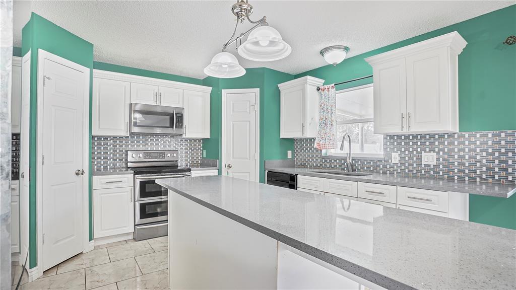 105 Caterham Way Kissimmee, FL 34758 - Photo 9 of 34 a kitchen with stainless steel appliances granite countertop a sink a stove a refrigerator cabinets and a window