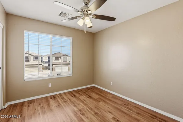 a view of an empty room with window and wooden floor