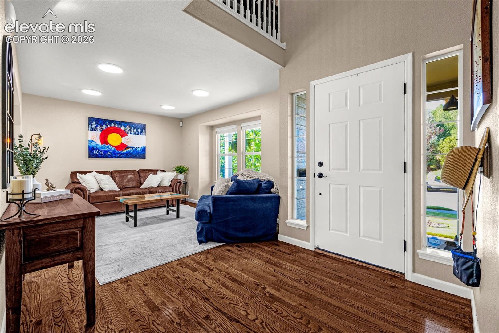 7985 Orchard Path Road Colorado Springs, CO 80919 - Photo 25 of 50 Hardwood flooring, recessed lighting, white paneled entry door, side windows, and a visible upper-level railing