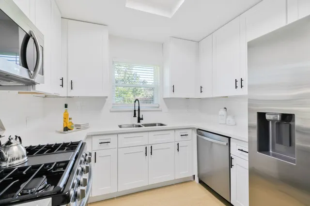 a kitchen with white cabinets and appliances