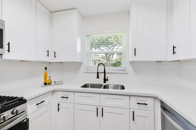 a kitchen with white cabinets and window